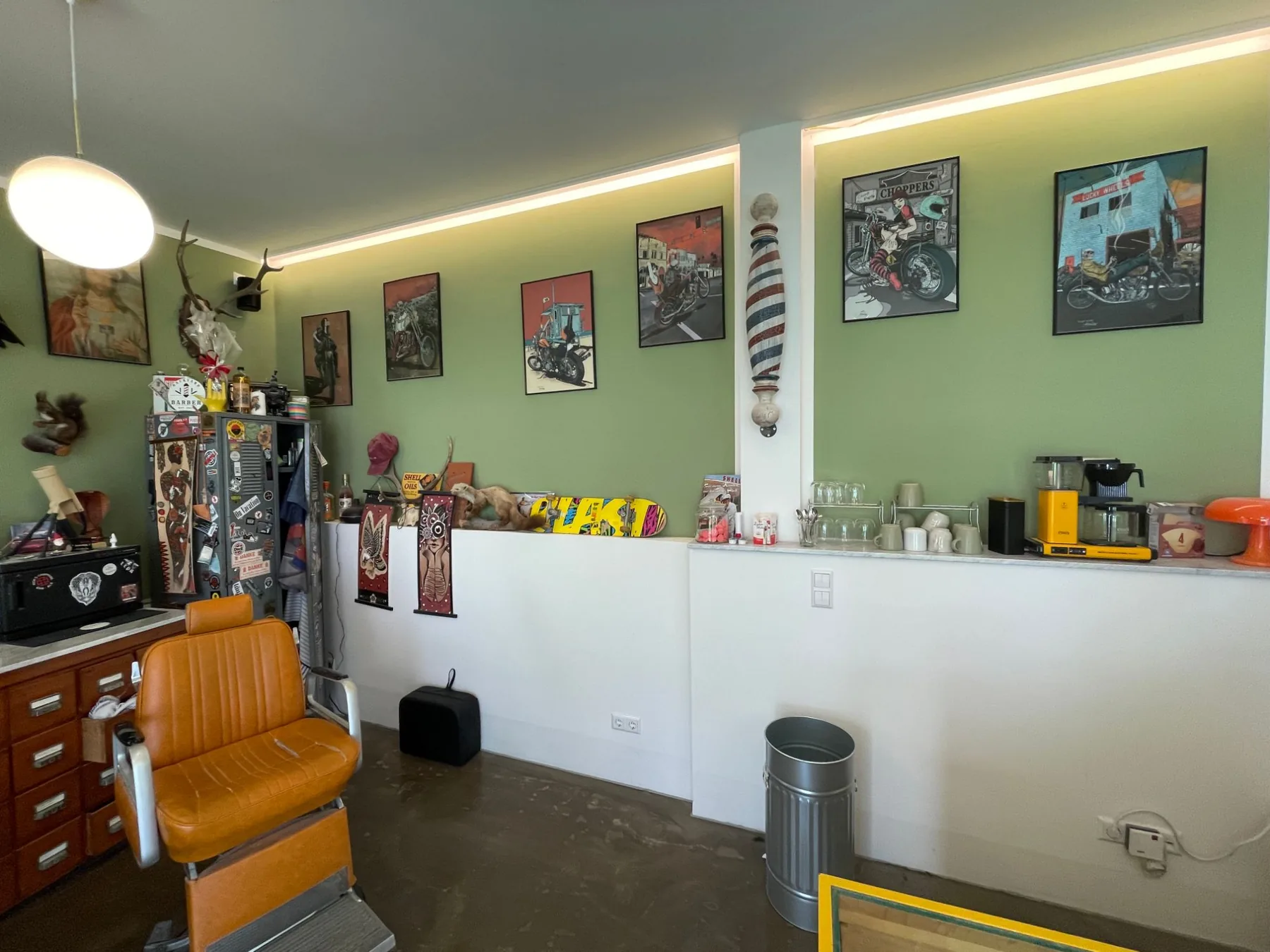 Oranger Barberstuhl vor der Wand mit Chopper-Illustrationen im Backyard Barber